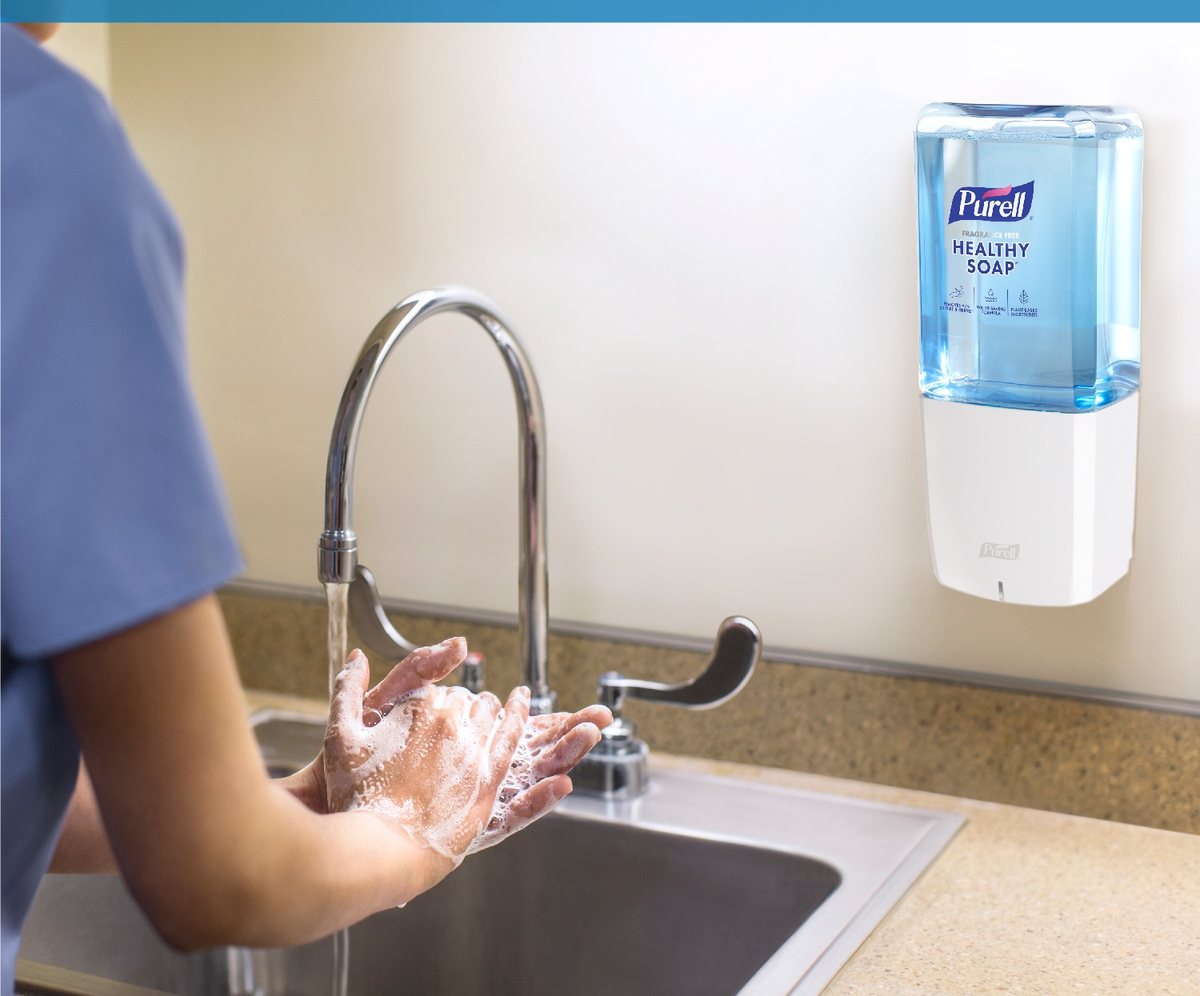 Hands washing under a faucet below a PURELL foam soap dispenser